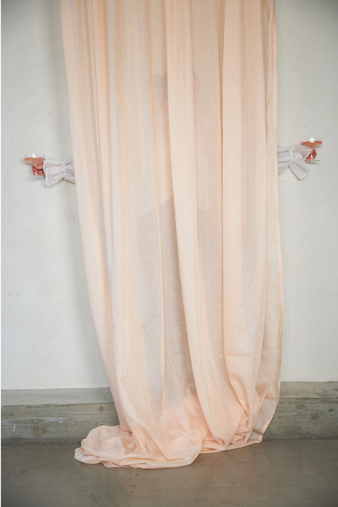 Beställ ett prov på vår allra tunnaste måttbeställda gardin. Den släpper in och mjukar upp ljuset samtidigt som den skärmar av direkt solljus, värme och insyn. Flamsäker fiber i 100% återvinningsbar polyester. På bilden ser du gardinen i färgen Blush. Gardinen skräddarsys för hand efter dina mått i Moshi Studios ateljé i Göteborg.